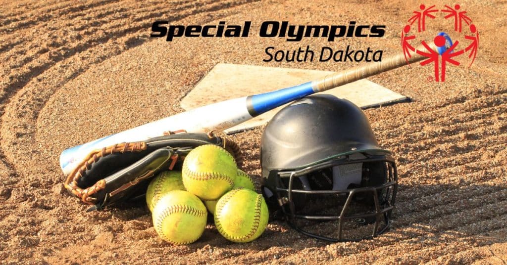 Softball bat, glove, helmet, and softballs are grouped together on a softball field.