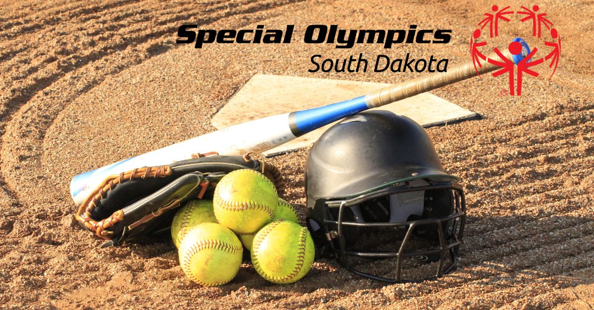 Softball bat, glove, helmet, and softballs are grouped together on a softball field.