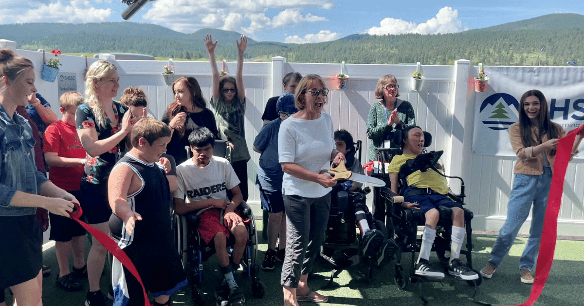 A group of people cheer after the ribbon is cut at the play area dedication ceremony.